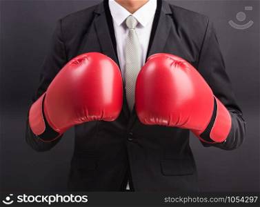 Young businessman with boxing gloves isolated on black background
