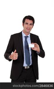 Young businessman with business card giving the thumbs-up