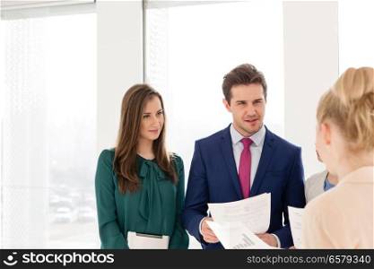 Young businessman with female colleagues discussing over documents in new office