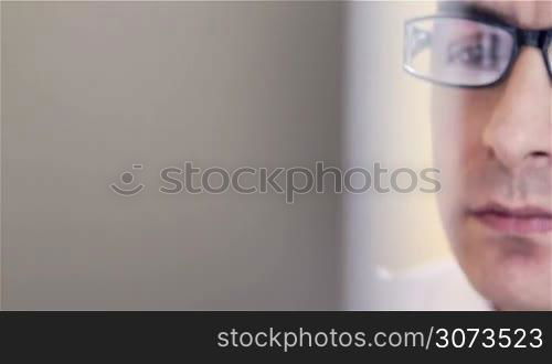 Young businessman with glasses working on computer - closeup, dolly shot.