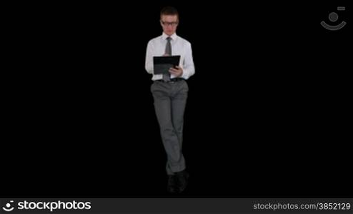 Young businessman with glasses writing on a clipboard and sitting, against black