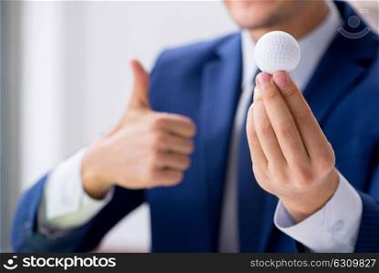 Young businessman with golf ball working in office