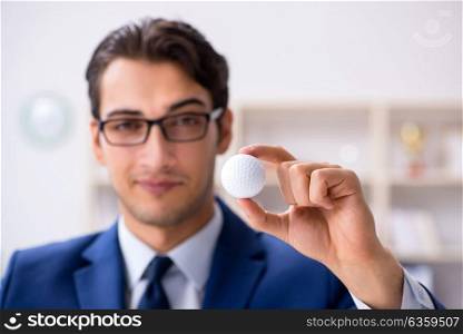 Young businessman with golf ball working in office