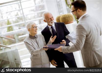 Young businessman with senior clients standing in  modern office