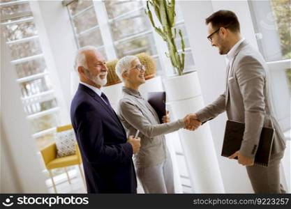 Young businessman with senior clients standing in  modern office