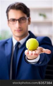 Young businessman with tennis ball working in office
