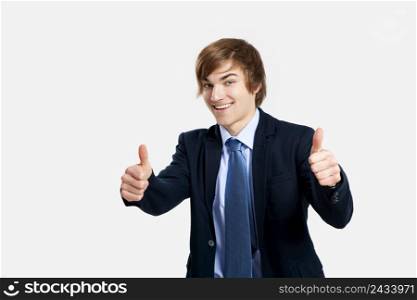 Young businessman with thumbs up, over a gray background