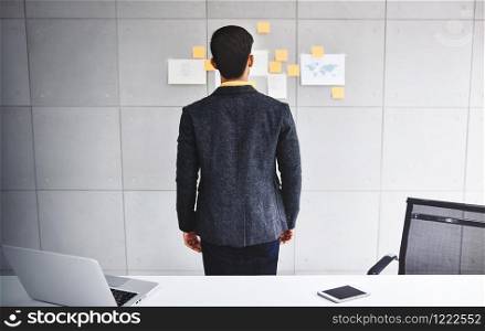 Young Businessman Working in Office Meeting Room. Man Analyzing Data Plans and Project. Concentrate on Document Note on Board