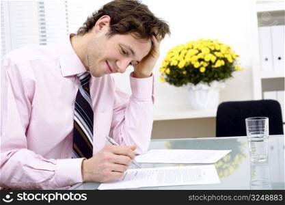Young businessman working in office, smiling. Horizontal version.