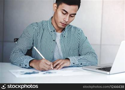 Young Businessman Working on Computer Laptop in Office. Sitting on Desk, Man in Casual Wear