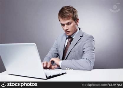 Young businessman working with laptop on a gray background