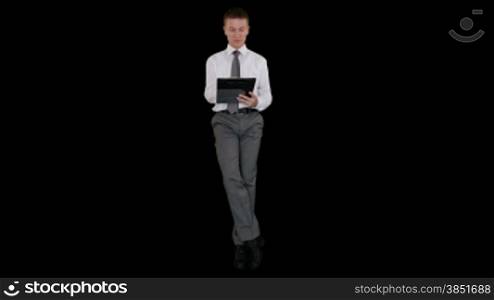 Young businessman writing on a clipboard and sitting, against black