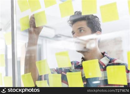 Young businessman writing on sticky notes in office