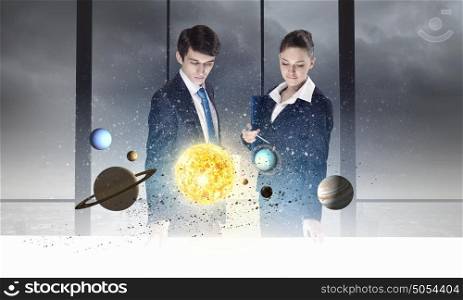 Young businesswoman and businessman and planets of space spinning around. Man and woman with the planets on table