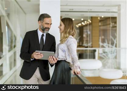 Young businesswoman and businessman look on digital tablet and discuss about new project in modern office