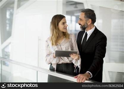 Young businesswoman and businessman look on digital tablet and discuss about new project in modern office
