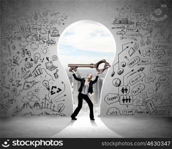 Young businesswoman and keyhole at background lifting big key above head. Find key to success