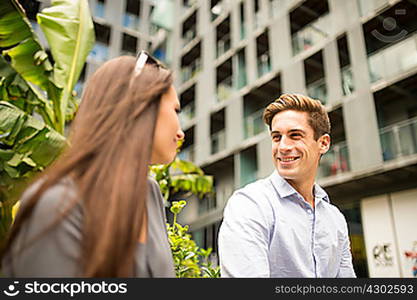 Young businesswoman and man chatting outside office, London, UK