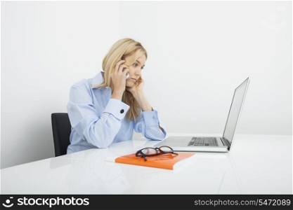 Young businesswoman answering cell phone in office