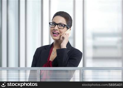Young businesswoman answering smart phone in office