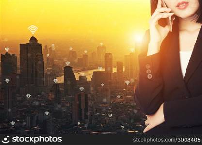 Young businesswoman calling on smartphone in smart city at sunset. - Business, communication, technology and people connection concept.