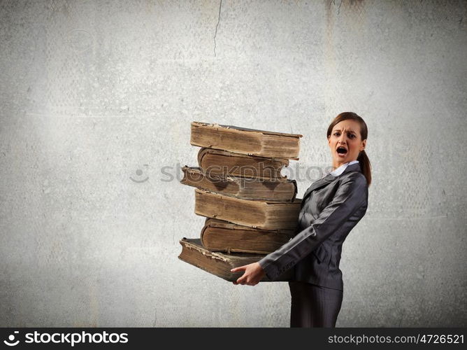 Young businesswoman carrying pile of old books. Master the science