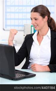 Young businesswoman delighted with what she can see on her computer screen