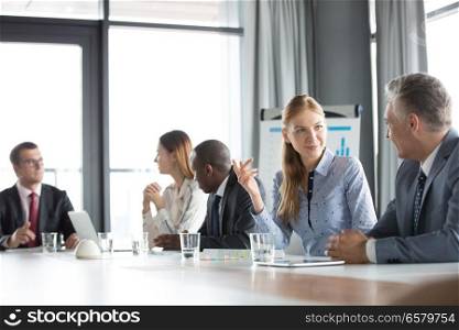Young businesswoman discussing with male colleague in board room