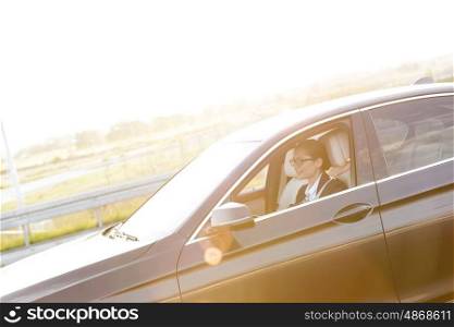 Young businesswoman driving car against sky