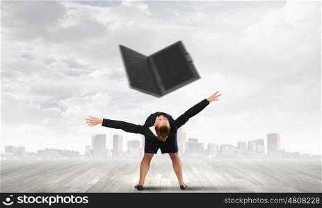 Young businesswoman evading back from flying laptop