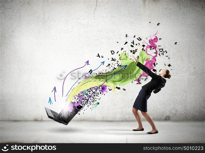 Young businesswoman evading colorful splashes flying from laptop. Impressive technology innovations
