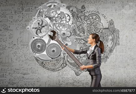 Young businesswoman fixing gears mechanism with wrench. Make it work