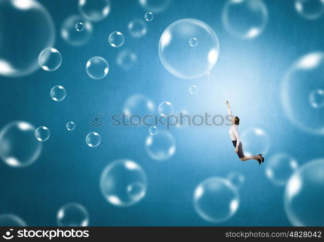 Young businesswoman flying high in sky on soap bubble. Woman fly in sky