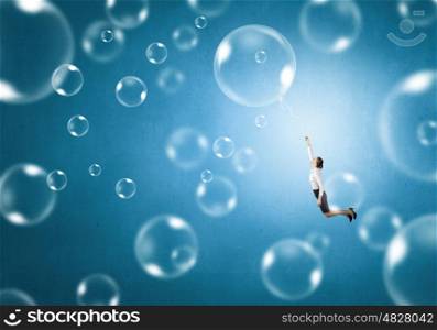 Young businesswoman flying high in sky on soap bubble. Woman fly in sky