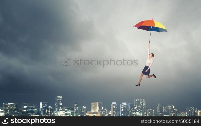 Young businesswoman flying high in sky on umbrella. Woman fly on umbrella