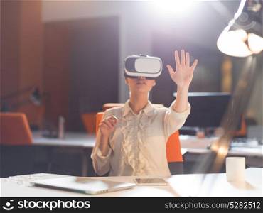 young businesswoman getting experience using VR-headset glasses of virtual reality at late night startup office building