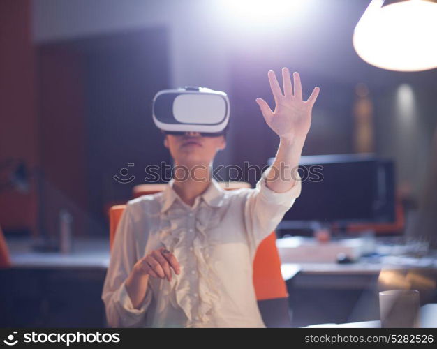 young businesswoman getting experience using VR-headset glasses of virtual reality at late night startup office building