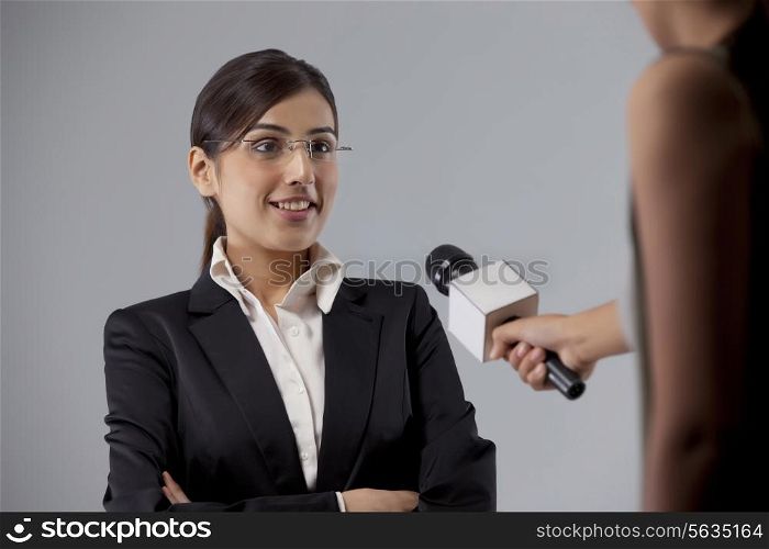 Young businesswoman giving interview to news reporter