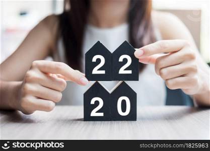 Young Businesswoman hands holding 2022 Happy New Year with house model on table office. New House, Financial, Property insurance, real estate, savings and New Year Resolution concepts