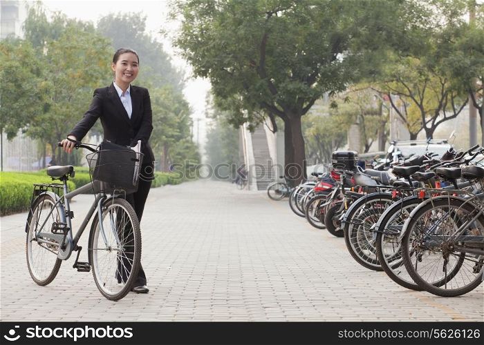 Young businesswoman holding a bicycle, sidewalk, Beijing
