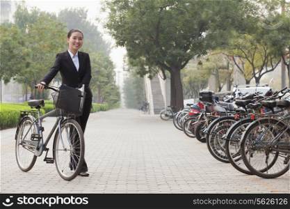 Young businesswoman holding a bicycle, sidewalk, Beijing