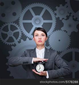 Young businesswoman holding a clock with clockwork background