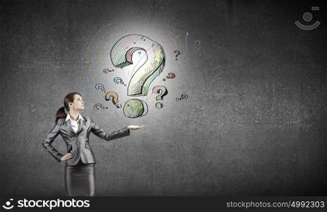 Young businesswoman holding question mark in palm. Have question