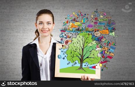 Young businesswoman holding wooden frame with business sketches