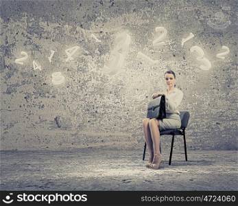 Young businesswoman. Image of businesswoman sitting on chair with suitcase in hands