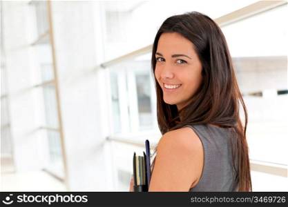 Young businesswoman in modern building holding files