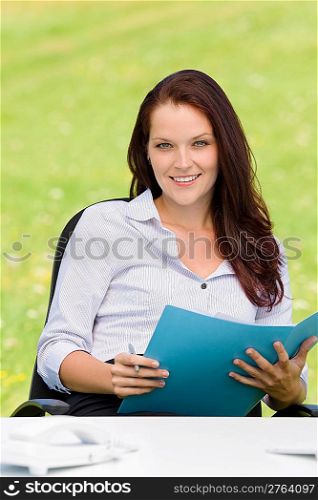 Young businesswoman in nature attractive smiling holding folder behind table