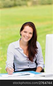 Young businesswoman in nature attractive smiling sitting behind computer table