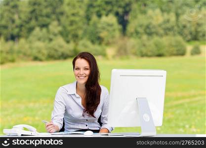 Young businesswoman in nature attractive smiling sitting behind computer table