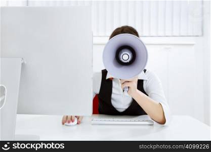 young businesswoman in office talking on the megaphone